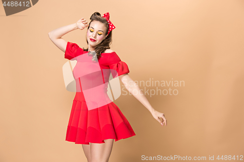 Image of Beautiful young woman with pinup make-up and hairstyle. Studio shot on pastel background