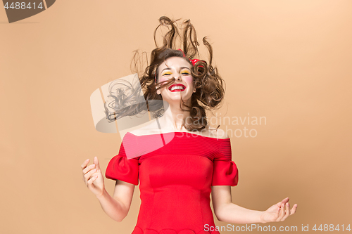 Image of Beautiful young woman with pinup make-up and hairstyle. Studio shot on pastel background