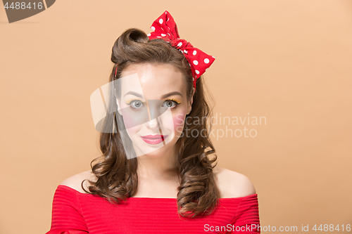 Image of Beautiful young woman with pinup make-up and hairstyle. Studio shot on pastel background