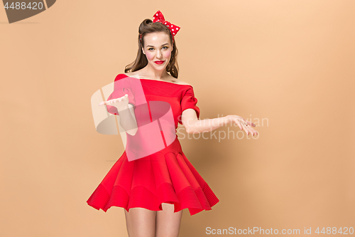 Image of Beautiful young woman with pinup make-up and hairstyle. Studio shot on pastel background