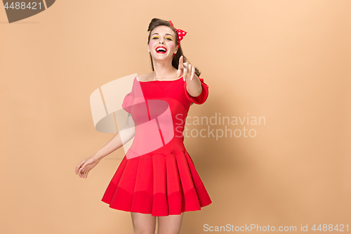 Image of Beautiful young woman with pinup make-up and hairstyle. Studio shot on pastel background