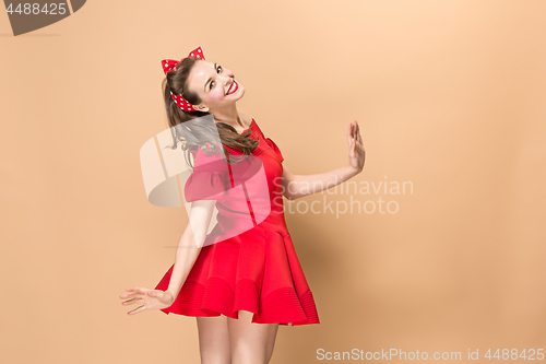 Image of Beautiful young woman with pinup make-up and hairstyle. Studio shot on pastel background