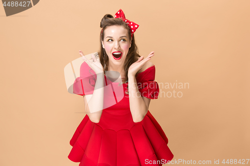 Image of Beautiful young woman with pinup make-up and hairstyle. Studio shot on pastel background