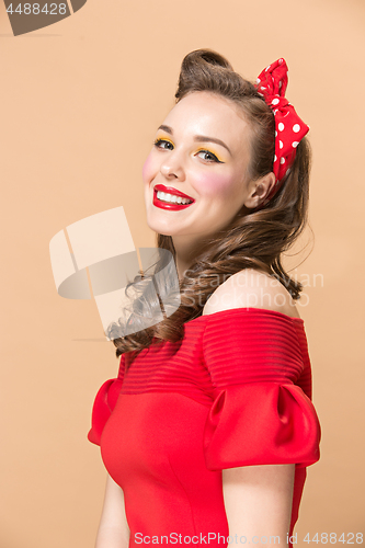 Image of Beautiful young woman with pinup make-up and hairstyle. Studio shot on pastel background