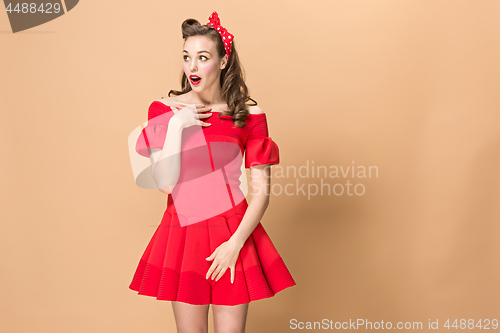 Image of Beautiful young woman with pinup make-up and hairstyle. Studio shot on pastel background