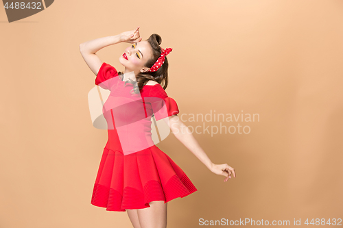 Image of Beautiful young woman with pinup make-up and hairstyle. Studio shot on pastel background