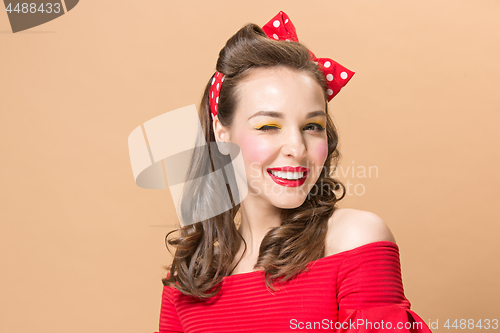 Image of Beautiful young woman with pinup make-up and hairstyle. Studio shot on pastel background