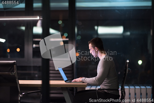 Image of man working on laptop in dark office