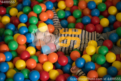 Image of boy having fun in hundreds of colorful plastic balls