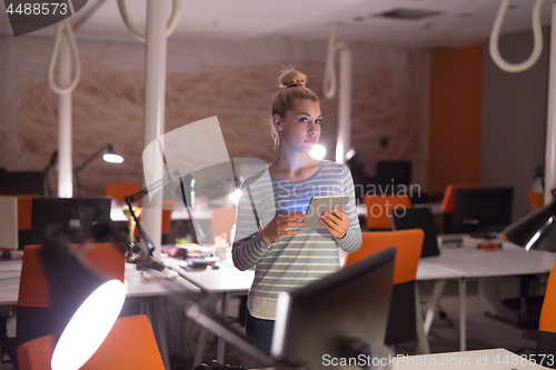 Image of woman working on digital tablet in night office