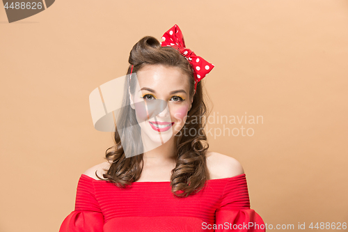 Image of Beautiful young woman with pinup make-up and hairstyle. Studio shot on pastel background