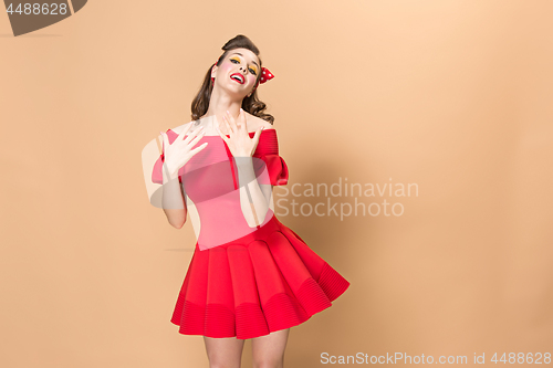 Image of Beautiful young woman with pinup make-up and hairstyle. Studio shot on pastel background