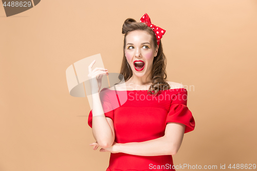 Image of Beautiful young woman with pinup make-up and hairstyle. Studio shot on pastel background