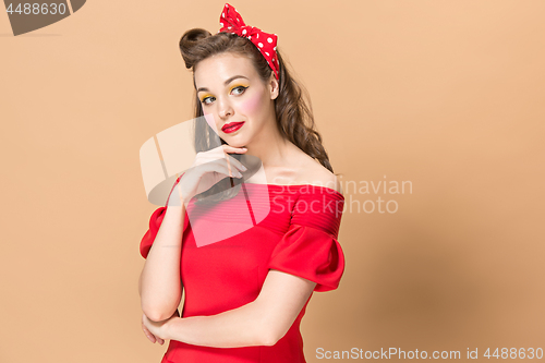 Image of Beautiful young woman with pinup make-up and hairstyle. Studio shot on pastel background