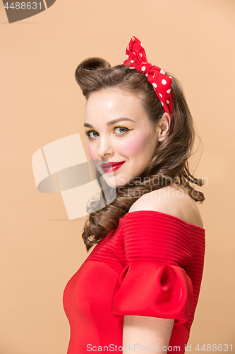 Image of Beautiful young woman with pinup make-up and hairstyle. Studio shot on pastel background