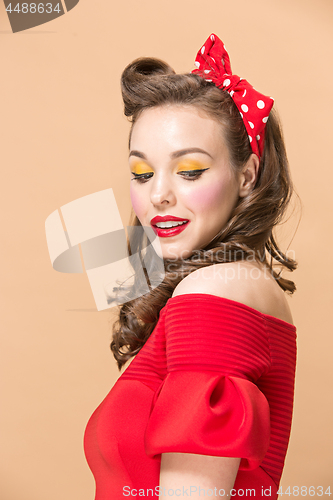 Image of Beautiful young woman with pinup make-up and hairstyle. Studio shot on pastel background