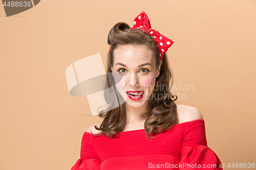 Image of Beautiful young woman with pinup make-up and hairstyle. Studio shot on pastel background