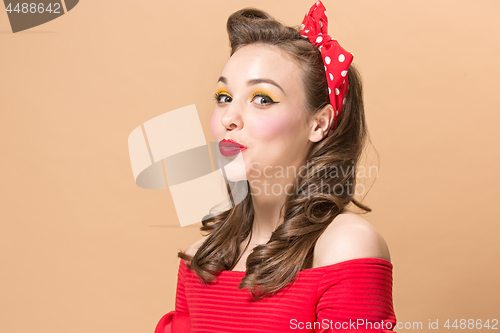 Image of Beautiful young woman with pinup make-up and hairstyle. Studio shot on pastel background