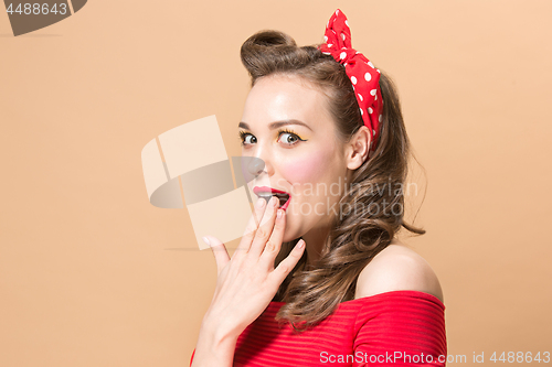 Image of Beautiful young woman with pinup make-up and hairstyle. Studio shot on pastel background