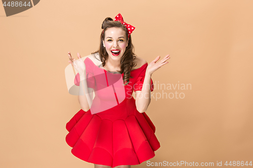 Image of Beautiful young woman with pinup make-up and hairstyle. Studio shot on pastel background