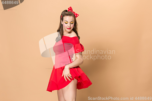 Image of Beautiful young woman with pinup make-up and hairstyle. Studio shot on pastel background