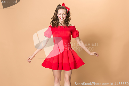 Image of Beautiful young woman with pinup make-up and hairstyle. Studio shot on pastel background