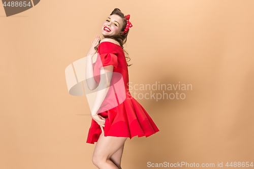 Image of Beautiful young woman with pinup make-up and hairstyle. Studio shot on pastel background