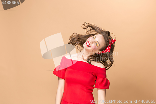 Image of Beautiful young woman with pinup make-up and hairstyle. Studio shot on pastel background