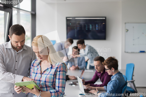 Image of Two Business People Working With Tablet in office