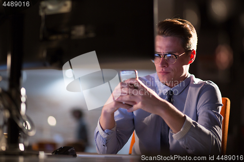 Image of man using mobile phone in dark office