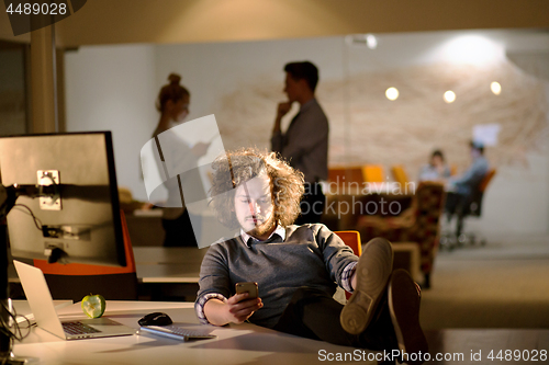 Image of businessman sitting with legs on desk at office