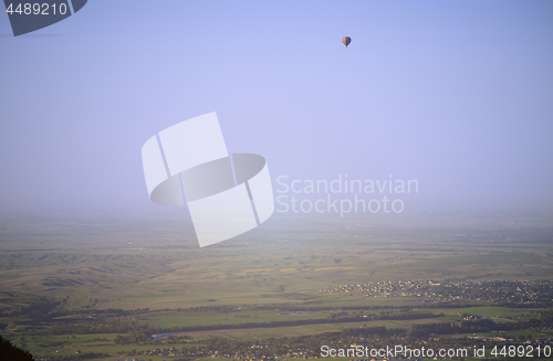 Image of Hot air balloon above the green field and villages