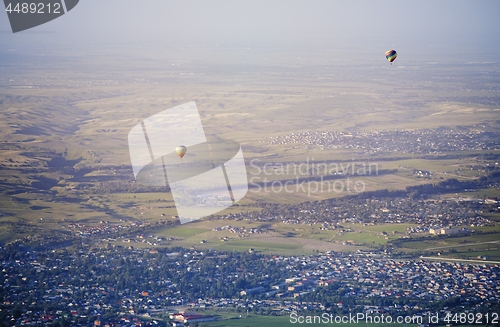 Image of Hot air balloons above the green field and villages