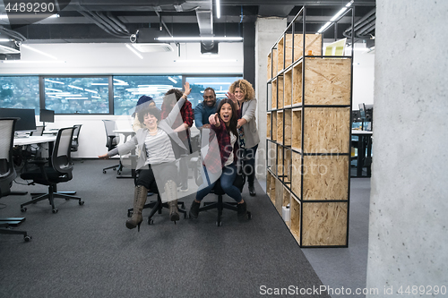 Image of multiethnics business team racing on office chairs