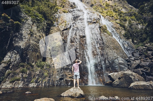 Image of Man standing against waterfall