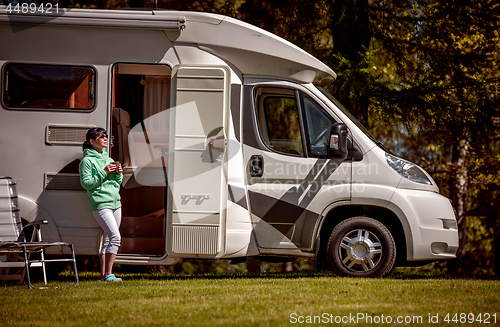 Image of Woman is standing with a mug of coffee near the camper RV.