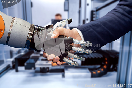 Image of Hand of a businessman shaking hands with a Android robot.