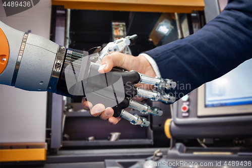 Image of Hand of a businessman shaking hands with a Android robot.