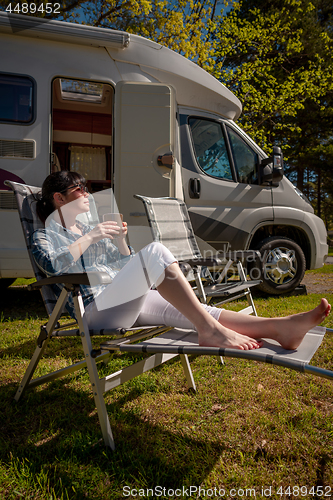 Image of Woman is standing with a mug of coffee near the camper RV.