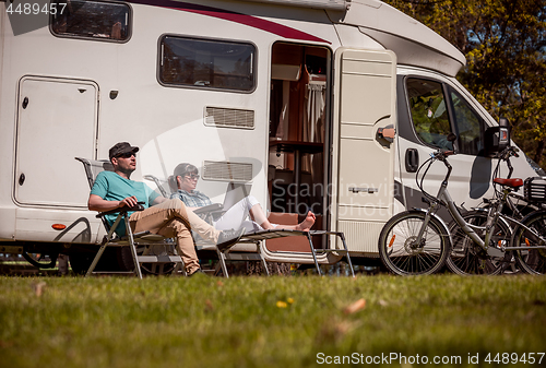 Image of Woman with a man resting near motorhomes in nature. Family vacat