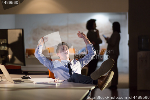 Image of businessman sitting with legs on desk at office