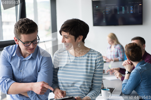 Image of Two Business People Working With Tablet in office