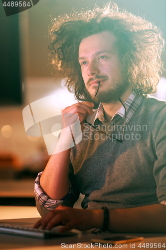 Image of man working on computer in dark office