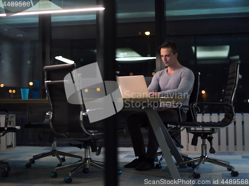 Image of man working on laptop in dark office