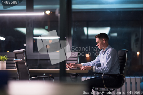 Image of man working on laptop in dark office