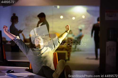 Image of businessman sitting with legs on desk at office