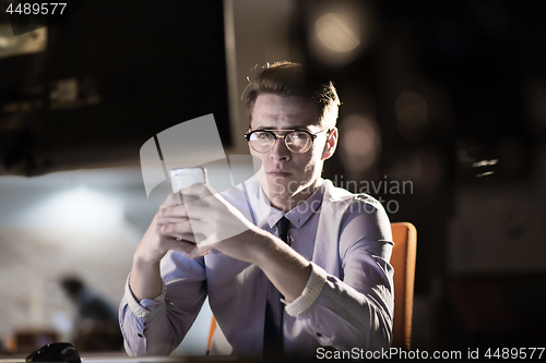 Image of man using mobile phone in dark office