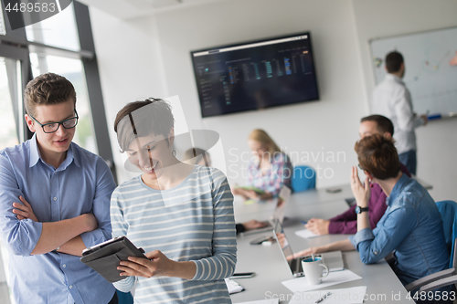 Image of Two Business People Working With Tablet in office