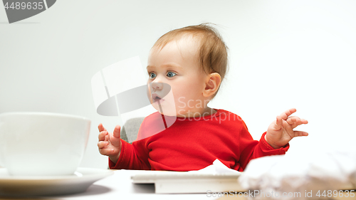 Image of Happy child baby girl toddler sitting with keyboard of computer isolated on a white background