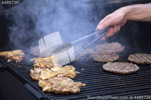 Image of Chef preparing burgers at the barbecue outdoors